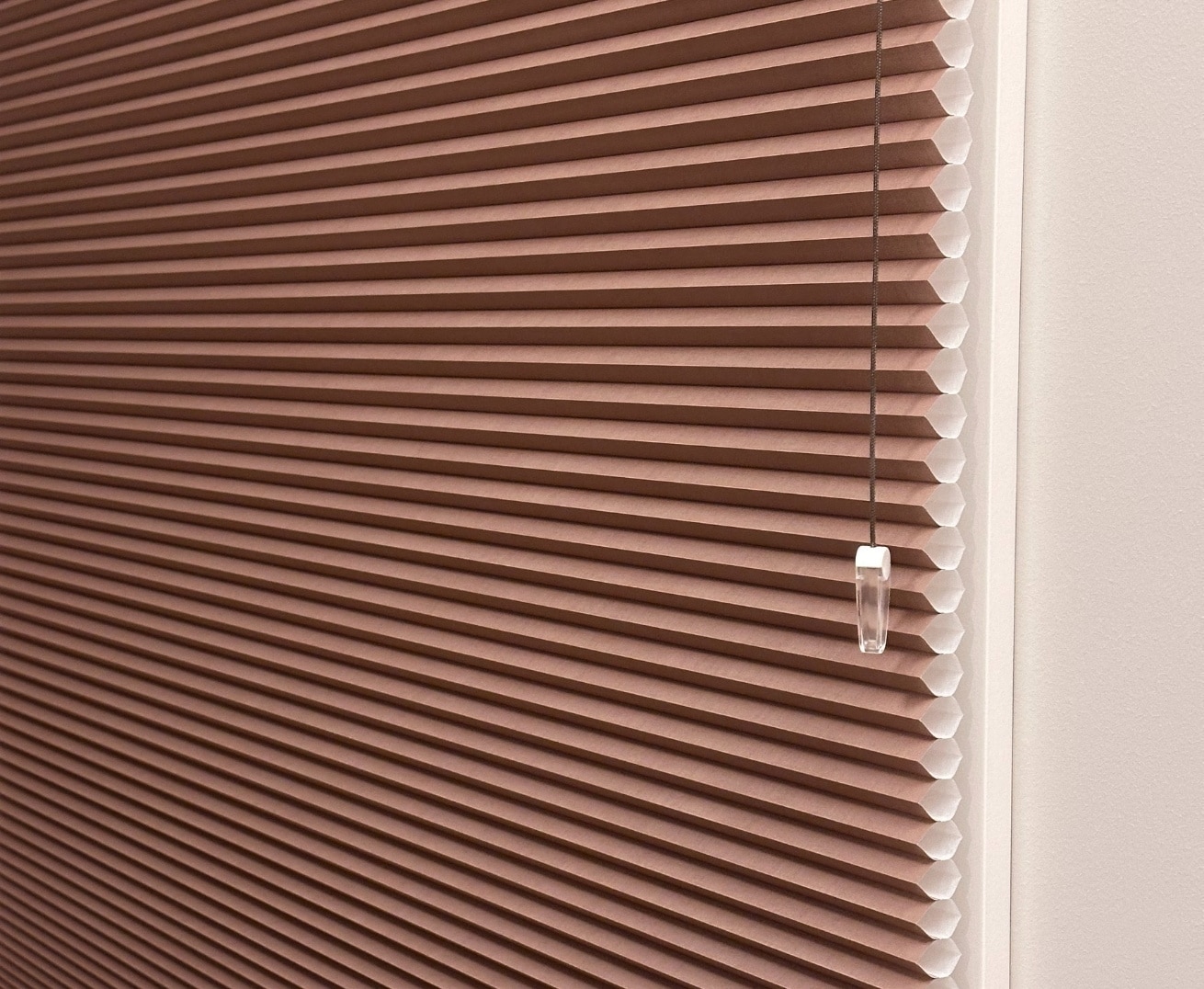 Brun mørkleggende plisségardin på et murhus – en moderne solskjermingsløsning.